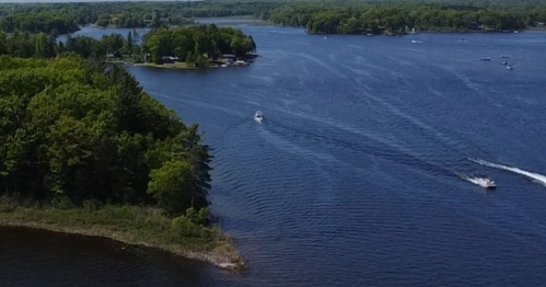 Aerial view of a serene lake with boats and lush green trees along the shoreline.