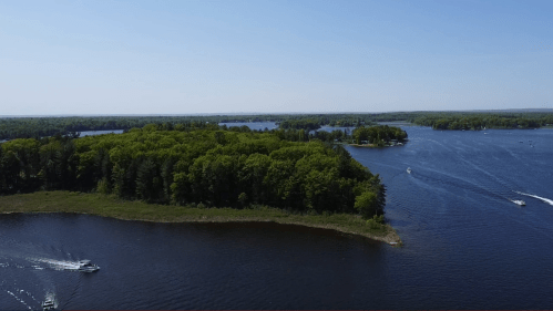 Aerial view of a serene lake surrounded by lush green trees and small boats navigating the water.