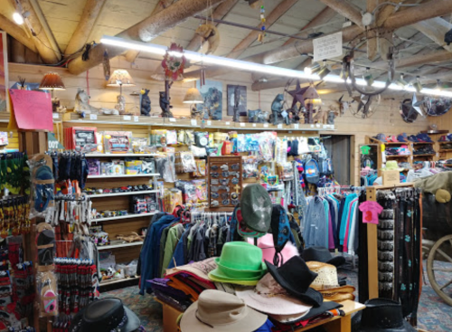A colorful gift shop filled with hats, clothing, and various souvenirs, featuring wooden beams and bright lighting.