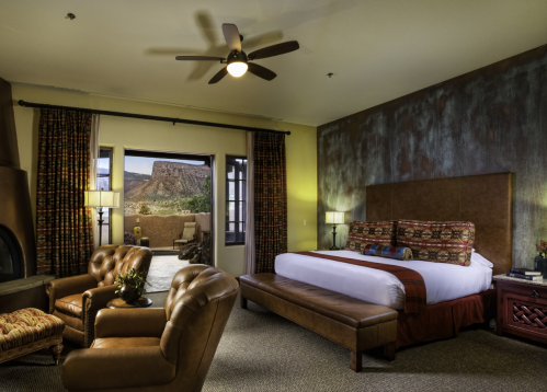 Cozy hotel room with a king bed, seating area, and large windows showcasing a scenic outdoor view.