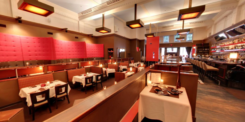 Elegant restaurant interior with pink and brown decor, tables set for dining, and a bar in the background.