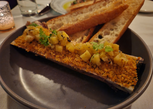 A plate featuring a bone filled with breadcrumb topping and diced apples, accompanied by toasted bread slices.