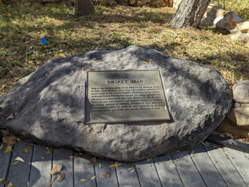 Plaque on a rock commemorating Smokey Bear, detailing his history and role in fire prevention.