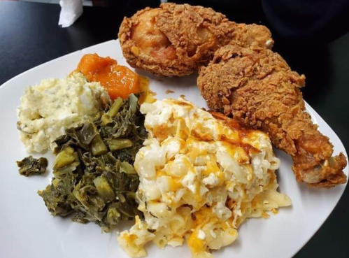 A plate of fried chicken, macaroni and cheese, collard greens, and a side of peach cobbler.