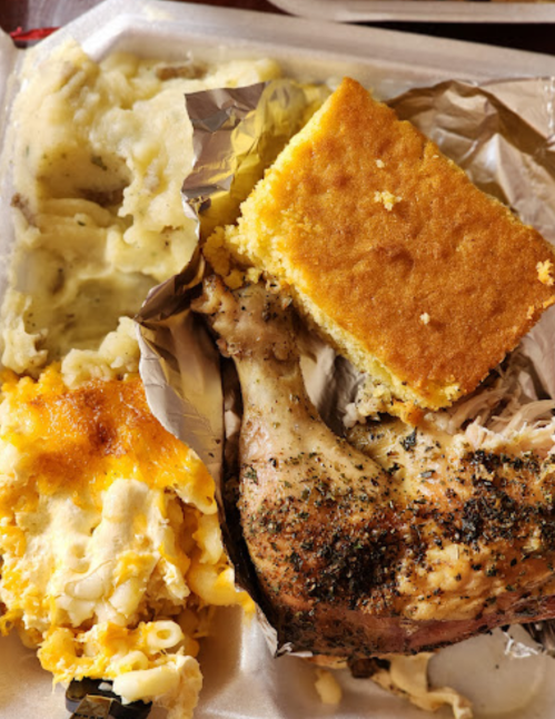 A plate featuring roasted chicken, cornbread, mashed potatoes, and macaroni and cheese.
