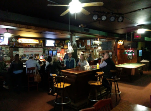 A cozy bar scene with patrons at the counter, a pool table, and warm lighting creating a welcoming atmosphere.