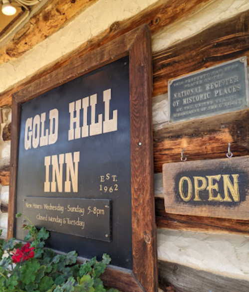 Sign for Gold Hill Inn, established 1962, with hours and "Open" sign displayed on a rustic wooden background.