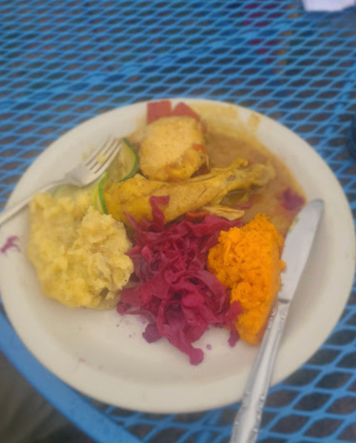A plate of food featuring chicken, yellow rice, red cabbage, and orange sweet potato, served on a blue table.
