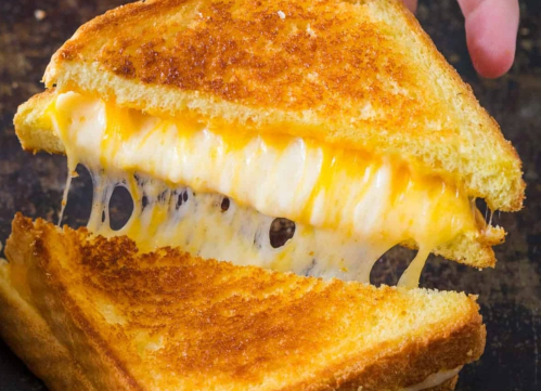 A gooey, melted cheese sandwich with golden, crispy bread, being pulled apart to reveal the stretchy cheese inside.