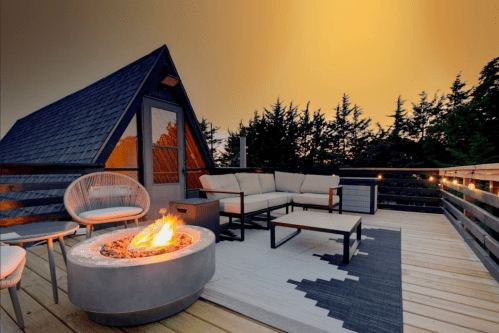 Cozy rooftop deck with modern seating, a fire pit, and a scenic view at sunset.