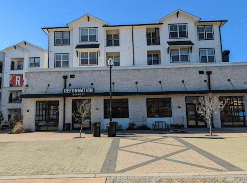 Exterior of Reformation Brewery with a modern building and outdoor seating area on a sunny day.