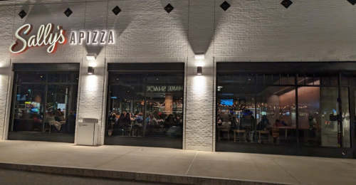 Exterior view of Sally's Apizza, featuring large windows and a lively dining atmosphere inside.
