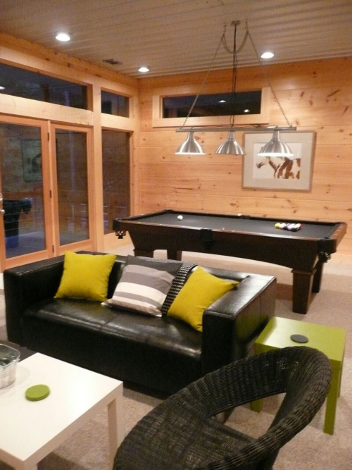 Cozy game room with a black pool table, leather sofa, and modern decor in a wooden interior.