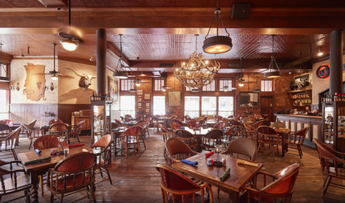 Cozy restaurant interior with wooden tables, chairs, and rustic decor, featuring warm lighting and a welcoming atmosphere.