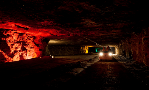 A dimly lit underground tunnel with colorful lights and a small vehicle in the foreground.