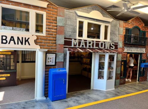 A colorful play area featuring a bank, a store named Marlow's, and a school, designed for children's imaginative play.