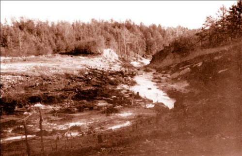 A sepia-toned landscape featuring a winding river surrounded by trees and rocky terrain.