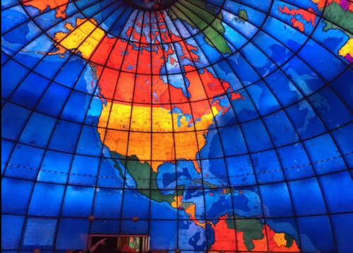 Colorful illuminated map of North America on a dome ceiling, featuring vibrant blue, orange, yellow, and green regions.