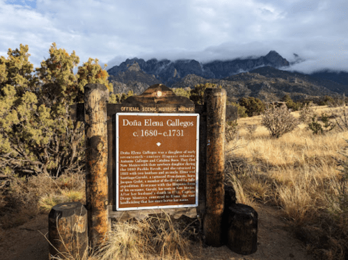 Sign for Doña Elena Gallegos, detailing her life from c. 1680 to c. 1731, with mountains in the background.
