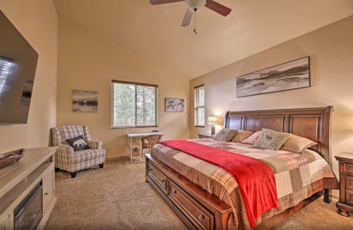 Cozy bedroom with a large bed, plaid bedding, a chair, and a window, featuring warm tones and soft lighting.