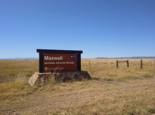 Sign for Maxwell National Wildlife Refuge in a grassy landscape under a clear blue sky.