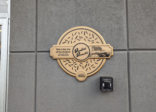 Plaque marking the site of the original Dunkin' Donuts, established in 1950, featuring a donut design.