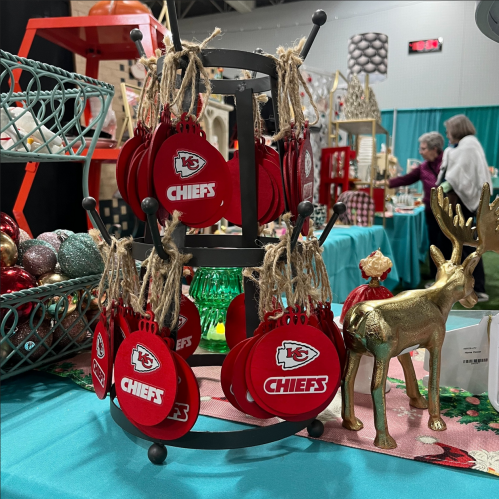 A display of red ornaments with "Chiefs" logos, hanging on a stand at a festive market.