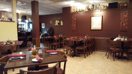 Cozy restaurant interior with wooden tables, red napkins, and warm lighting, featuring a welcoming atmosphere.