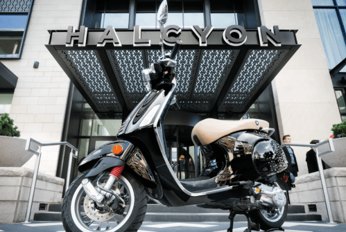 A stylish scooter parked in front of the Halcyon building, showcasing modern architecture and design.