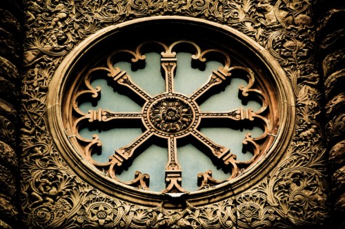 Ornate circular window with intricate floral and geometric designs, featuring a central sun motif.