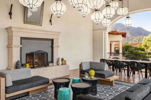 Cozy lounge area with modern furniture, decorative lanterns, and a fireplace, overlooking a mountain view.