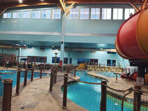 Indoor water park featuring a pool, water slides, and play areas, with colorful structures and safety barriers.