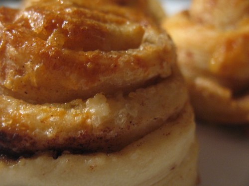 Close-up of golden-brown cinnamon rolls with a soft, flaky texture and a hint of cinnamon visible.