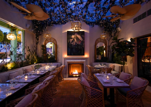 Cozy restaurant interior with elegant seating, a fireplace, and decorative plants under soft lighting.