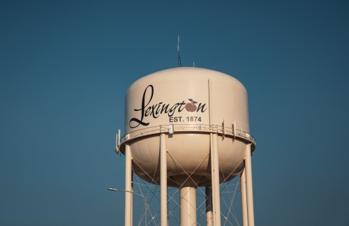 Water tower with "Lexington EST. 1874" written on it against a clear blue sky.