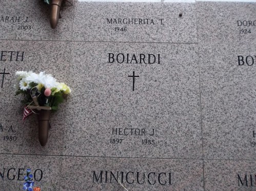 A granite grave marker with the name "Boiardi" and flowers, honoring Margherita T. and Hector J. Minicucci.