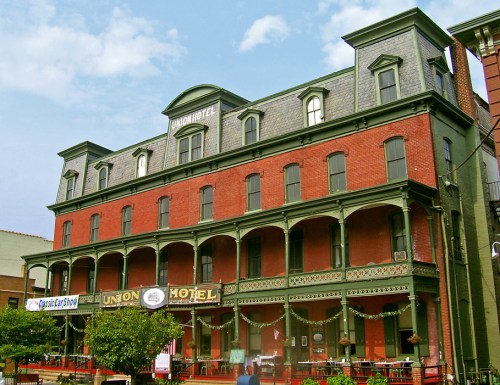 Historic Union Hotel with red brick facade, green trim, and covered porch, set against a blue sky.