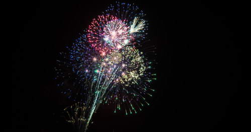 Colorful fireworks burst in the night sky, creating a vibrant display of lights and patterns.