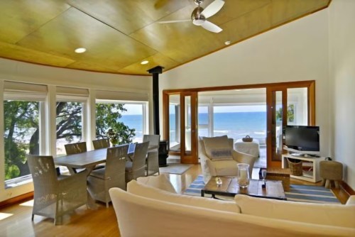 Bright, modern living space with ocean views, featuring a dining table, comfortable seating, and large windows.