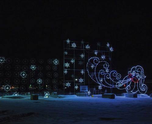 Colorful holiday lights display featuring snowflakes and a whimsical design in a nighttime setting.