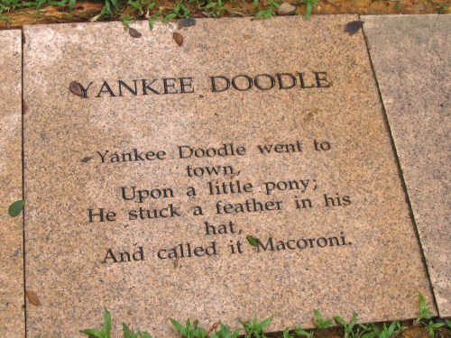 A stone plaque inscribed with the lyrics to "Yankee Doodle," featuring decorative leaves around it.