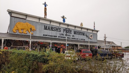 Exterior of Marsh's Free Museum in Long Beach, WA, featuring a large bear sign and various antique displays.