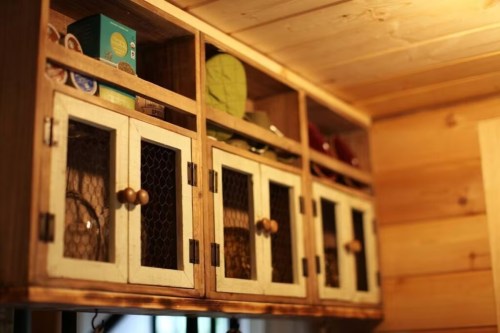 Wooden cabinet with glass doors, displaying various items and organized neatly in a cozy interior setting.