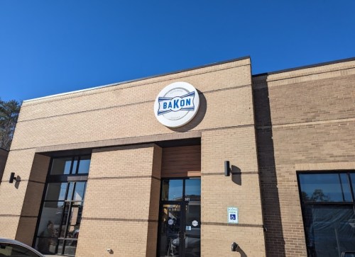 Exterior of a building with a sign that reads "BAKON" against a clear blue sky.