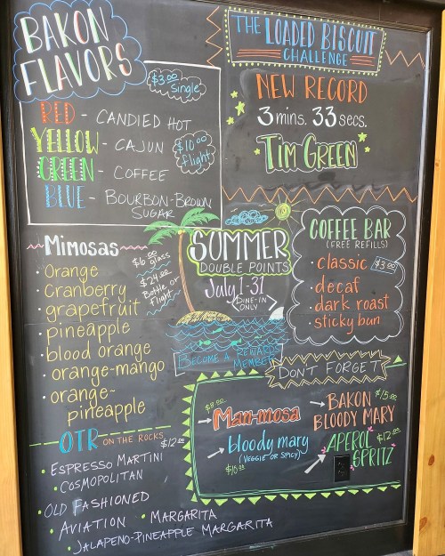 Chalkboard menu featuring bacon flavors, mimosa options, coffee bar details, and a challenge announcement.