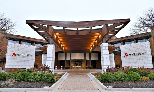 Modern Marriott hotel entrance with a distinctive roof design, surrounded by landscaped greenery.