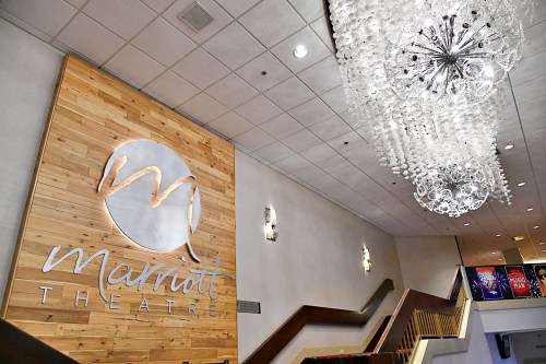 Interior of Marriott Theatre featuring a wooden wall sign and a large chandelier above.