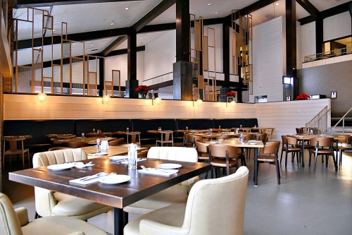 Modern restaurant interior with wooden beams, elegant tables, and festive decorations. Bright and spacious atmosphere.