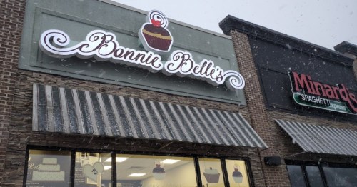 Sign for "Bonnie Belle's" cupcake shop with snow falling outside, next to "Minardi's Spaghetti Express" restaurant.