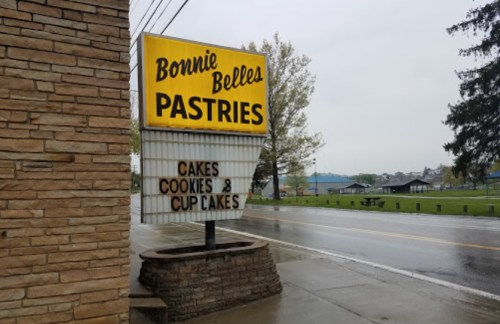 Sign for Bonnie Belles Pastries displaying "Cakes, Cookies, Cup Cakes" on a rainy day.